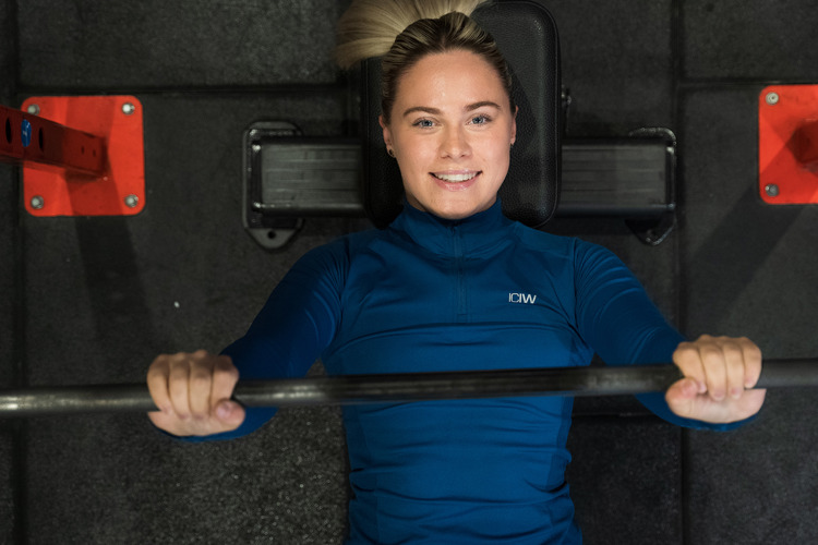 Kvinna kör skivstång liggande på gymmet