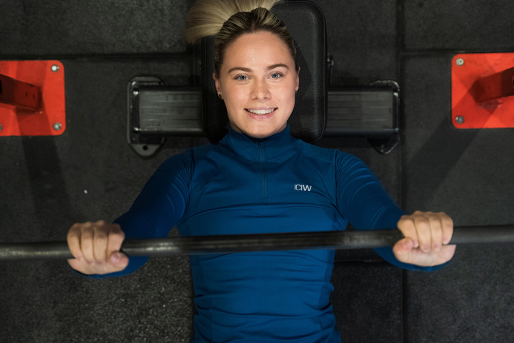 Kvinna kör skivstång liggande på gymmet