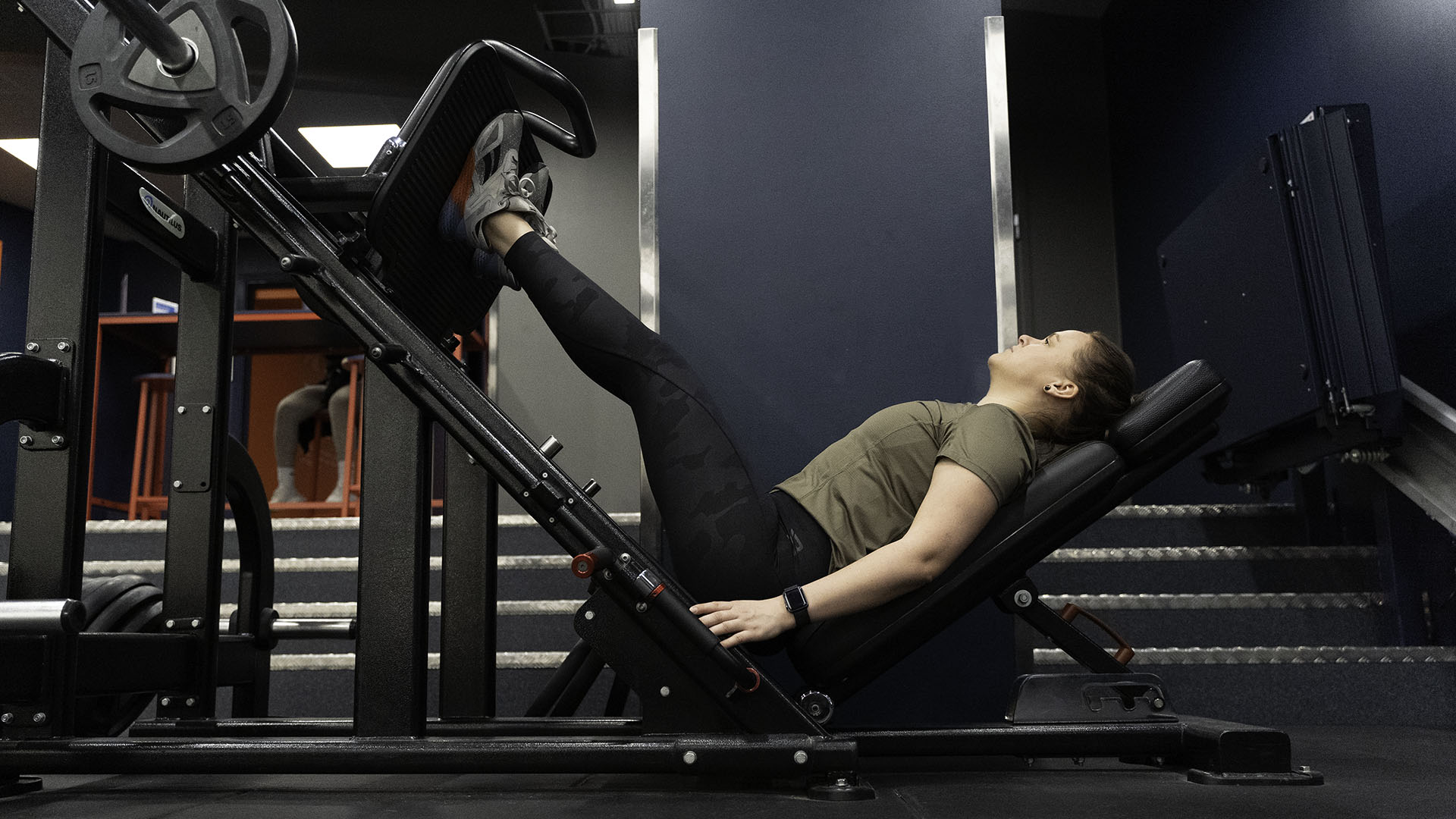 Kvinna gör benpress på gymmet i en styrkemaskin