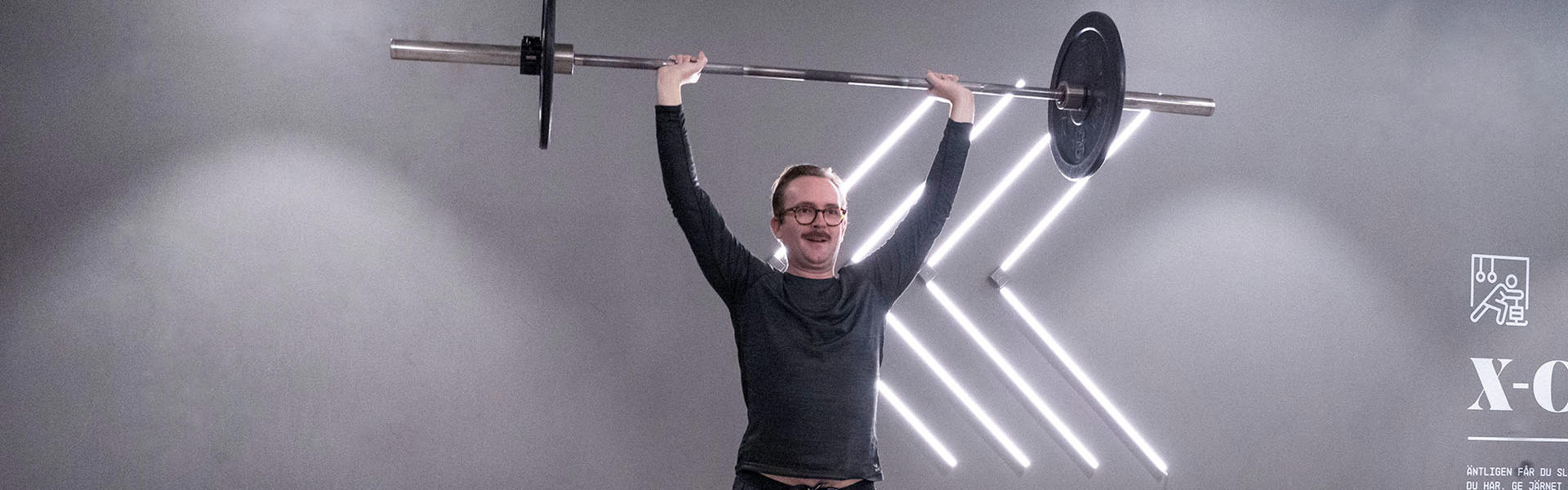 Man kör funktionell press med skivstång på gymmet